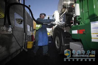 一名工人正在給垃圾車(chē)加“氣”